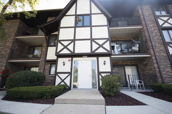Front view of a multi-story building with balconies and a white door.