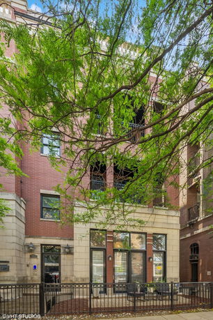 Front view of a multi-story brick building with balconies and large windows.