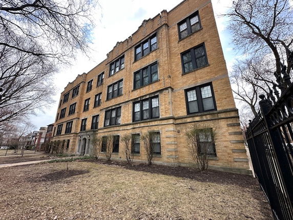 Front view of a four-story brick apartment building with multiple windows.