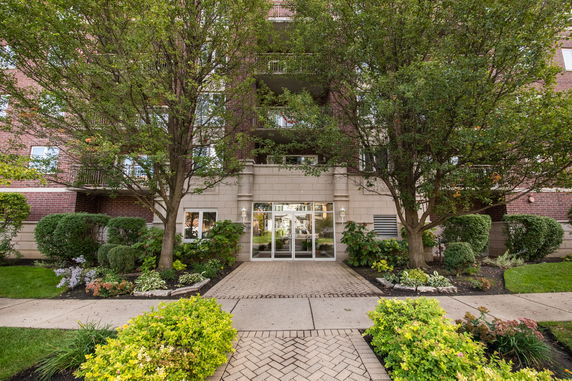 Front view of an apartment building with a brick facade and landscaped entrance.