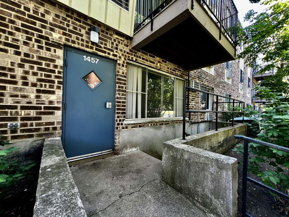 Front view of a multi-story brick building with balconies and a blue door numbered 1457.