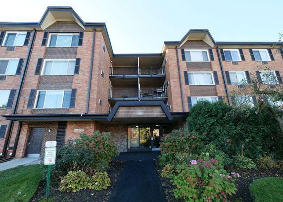 Front view of a multi-story brick apartment building with balconies.