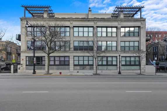 Front view of a multi-story building with large windows and a flat roof.
