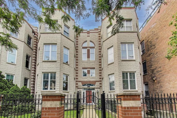 Front view of a multi-story brick apartment building with multiple windows and a central entrance.