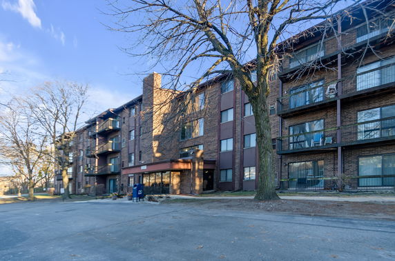 Front view of a multi-story brick apartment building with balconies.