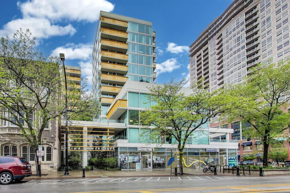 Front view of a modern multi-story building with glass and yellow accents.