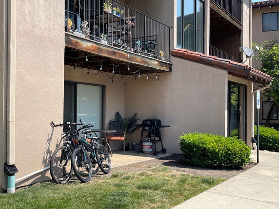 Front view of an apartment with balconies and a patio on the ground floor.