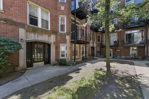 Front view of a multi-story brick apartment building with balconies.