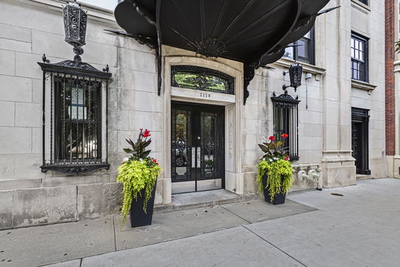 Front view of a building entrance with decorative ironwork and large planters.
