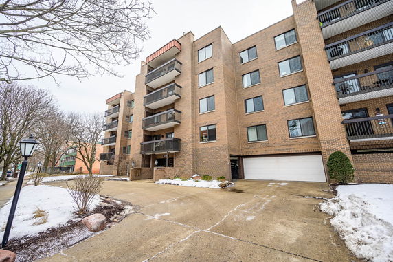 Front view of a multi-story brick apartment building with balconies.