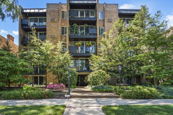 Front view of a multi-story brick apartment building with balconies.
