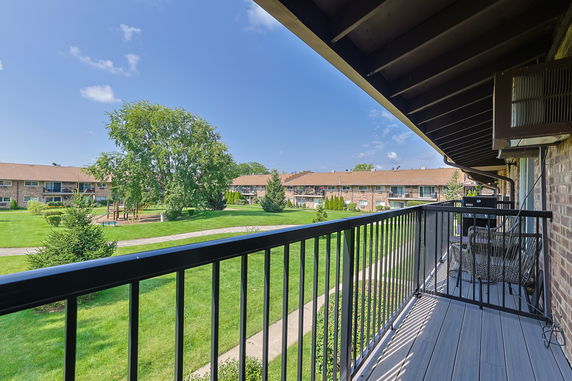 View from a balcony overlooking a grassy area with adjacent residential buildings.