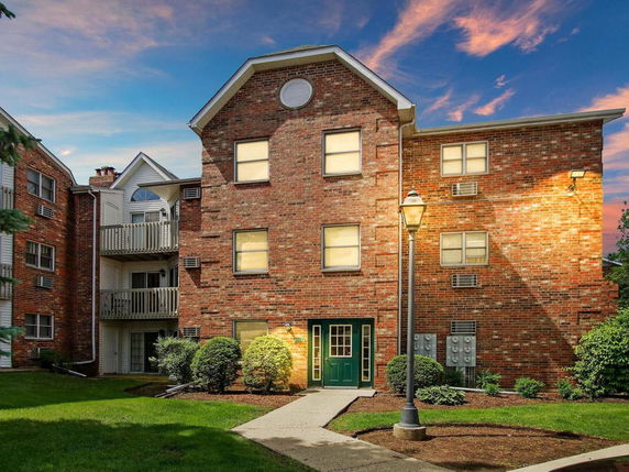 Front view of a brick multi-story apartment building with balconies.