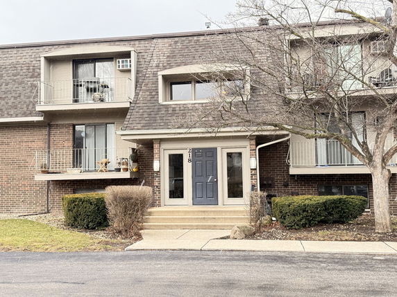 Front view of a multi-story residential building with balconies and a central entrance.