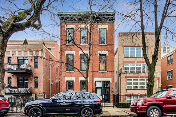 Front view of a three-story brick building with large windows.