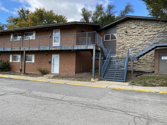 Front view of a two-story brick building with metal stairs and railing.