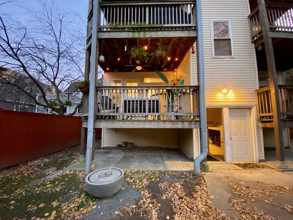 Back view of a multi-story house with balconies and an open area beneath.