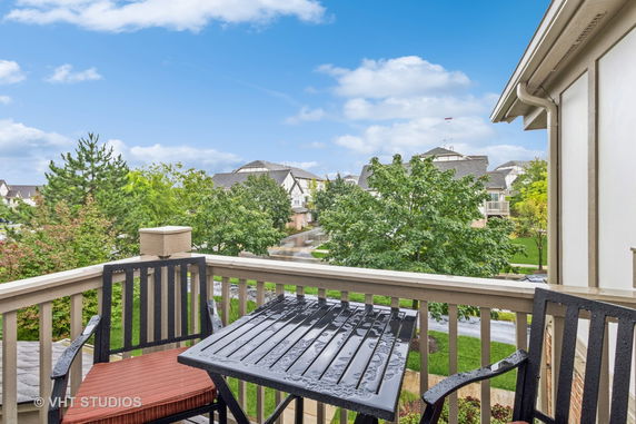 View from a balcony overlooking a residential area with houses and trees.