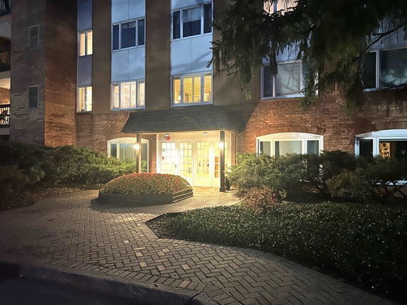 Front view of a building entrance at night with illuminated doorway and windows.