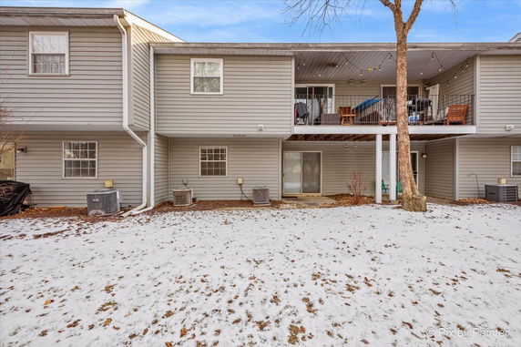 Back view of a two-story house with patios and snow-covered ground.