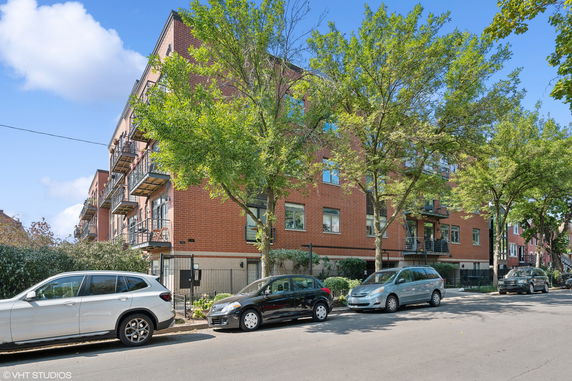 Front view of a multi-story brick apartment building with balconies.