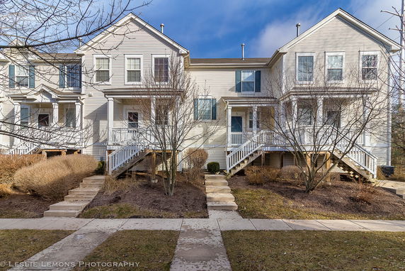 Front view of a two-story townhouse building with multiple entrances and stairs.