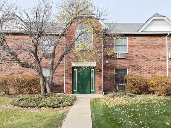 Front view of a two-story brick building with a green door.