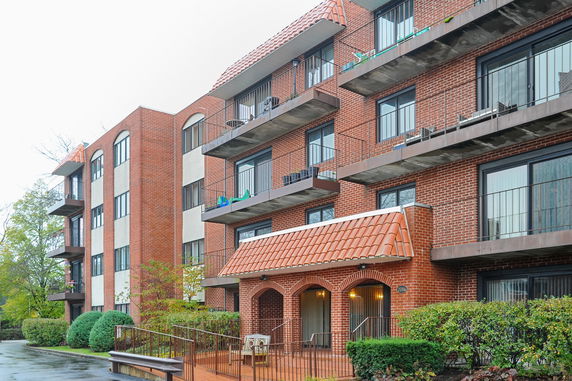 Front view of a multi-story brick apartment building with balconies.