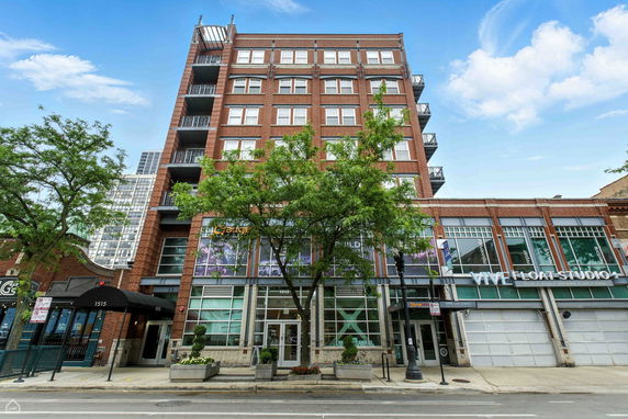Front view of a multi-story brick building with large windows and balconies.