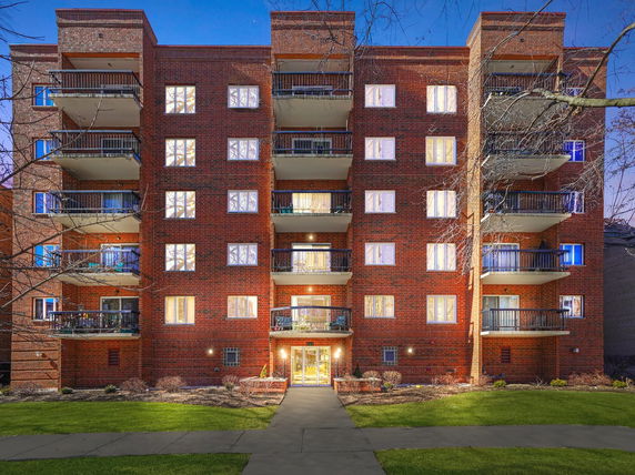 Front view of a multi-story brick apartment building with balconies.