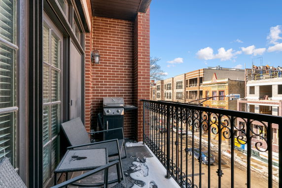 View of surrounding buildings from a balcony with brick walls and a grill.