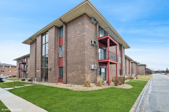 Front view of a multi-story brick building with balconies and large windows.