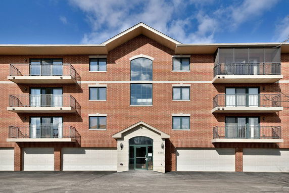 Front view of a multi-story building with brick facade and balconies.