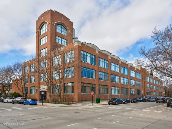 Front view of a multi-story brick building on a street corner.