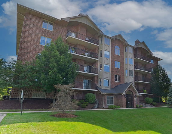 Front view of a multi-story brick apartment building with balconies.