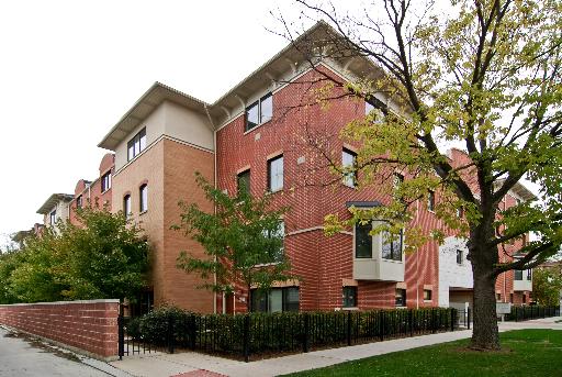 Front view of a multi-story brick building with trees and a sidewalk.