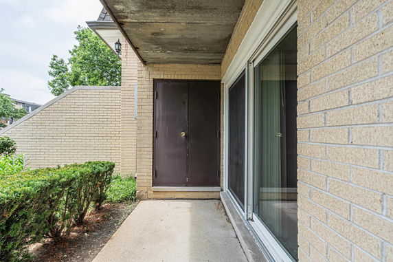 Front view of a brick building entrance with a sliding glass door.