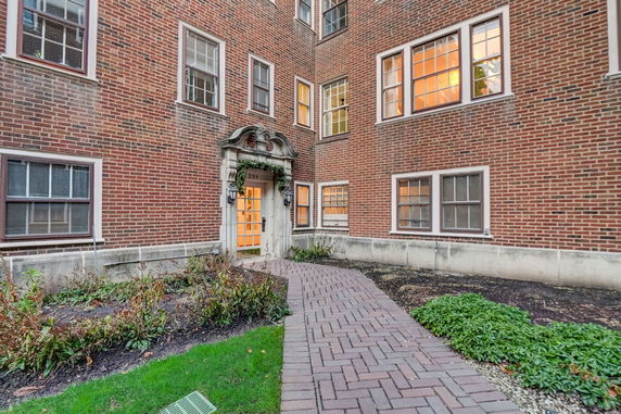 Front view of a brick apartment building with multiple windows and a central entrance.