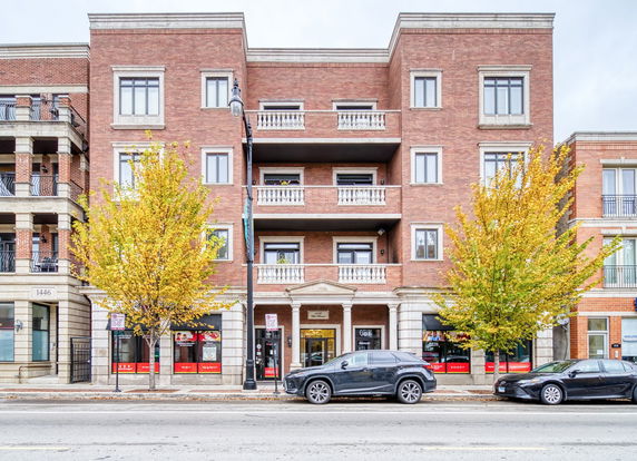 Front view of a multi-story brick building with balconies and large windows.