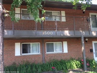 Front view of a two-story brick building with a balcony and the number 1500 displayed.