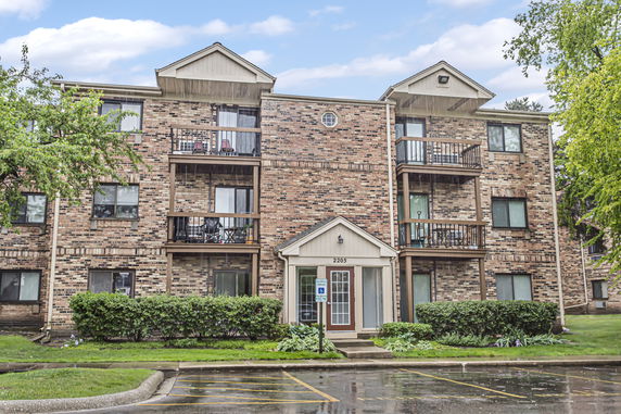 Front view of a three-story brick apartment building with balconies.