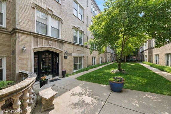 Front view of a multi-story brick apartment building with courtyard.
