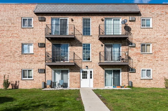 Front view of a brick apartment building with balconies and a central entrance.