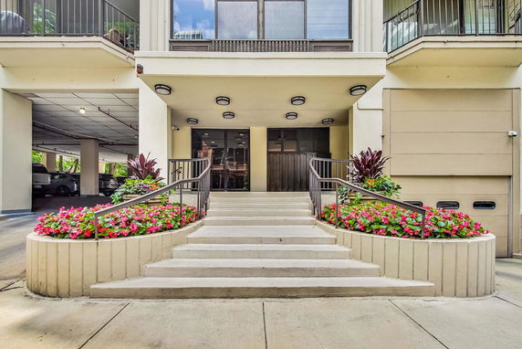 Front entrance of a building with stairs and flower beds.