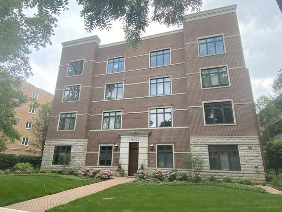 Front view of a four-story brick apartment building with large windows.