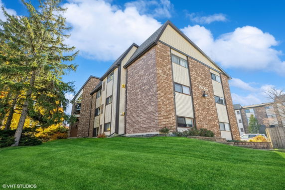 Front view of a multi-story brick apartment building with a sloped roof.