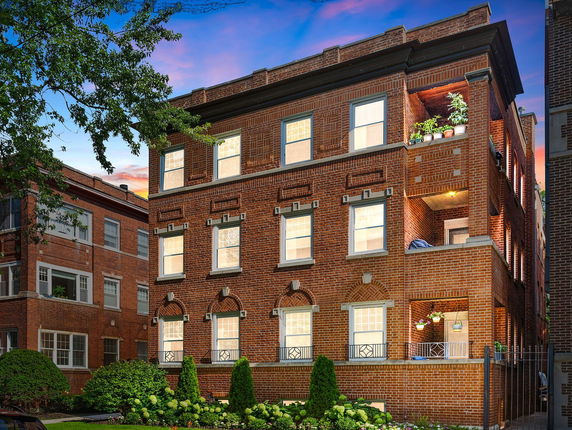 Front view of a multi-story brick building with multiple windows and balconies.