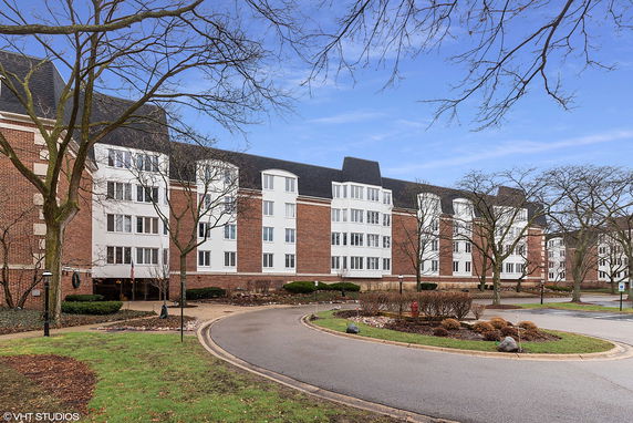Front view of a multi-story apartment building with brick and white facade.