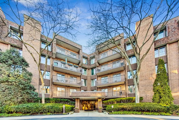 Front view of a multi-story apartment building with balconies and entrance awning.
