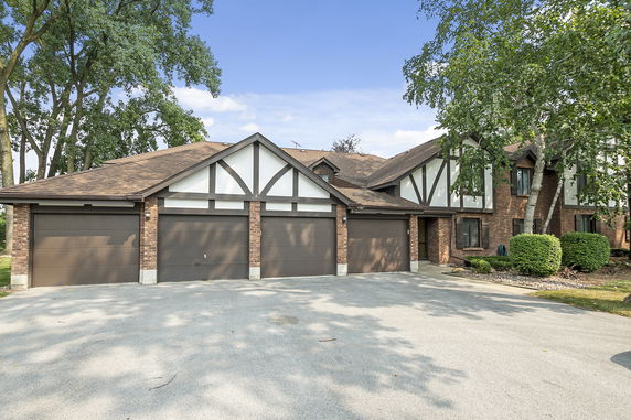Front view of a house with a three-car garage and Tudor-style architecture.